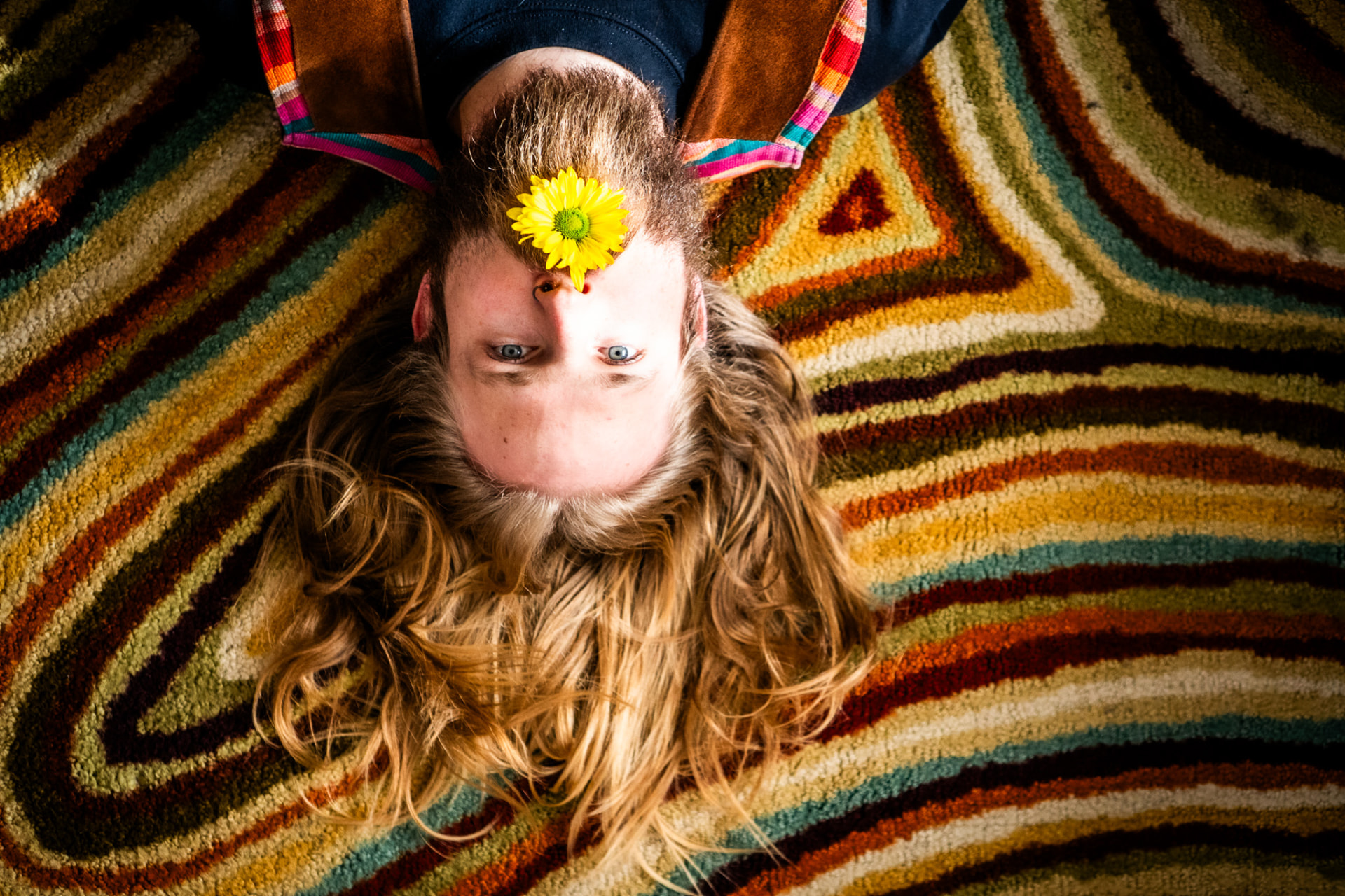 Overhead portrait on a striped rug with a daisy