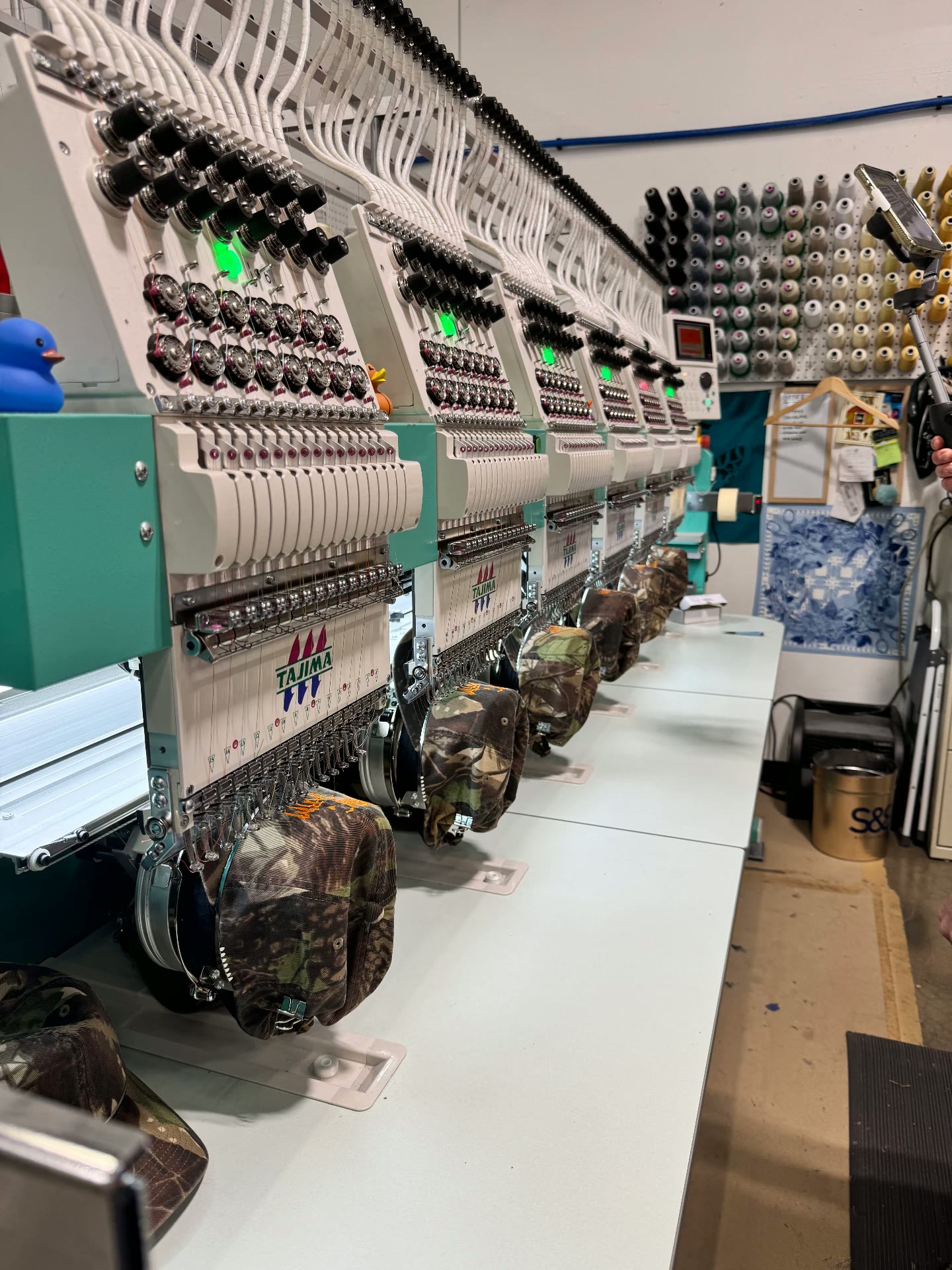 Row of Tajima embroidery heads stitching camo hats