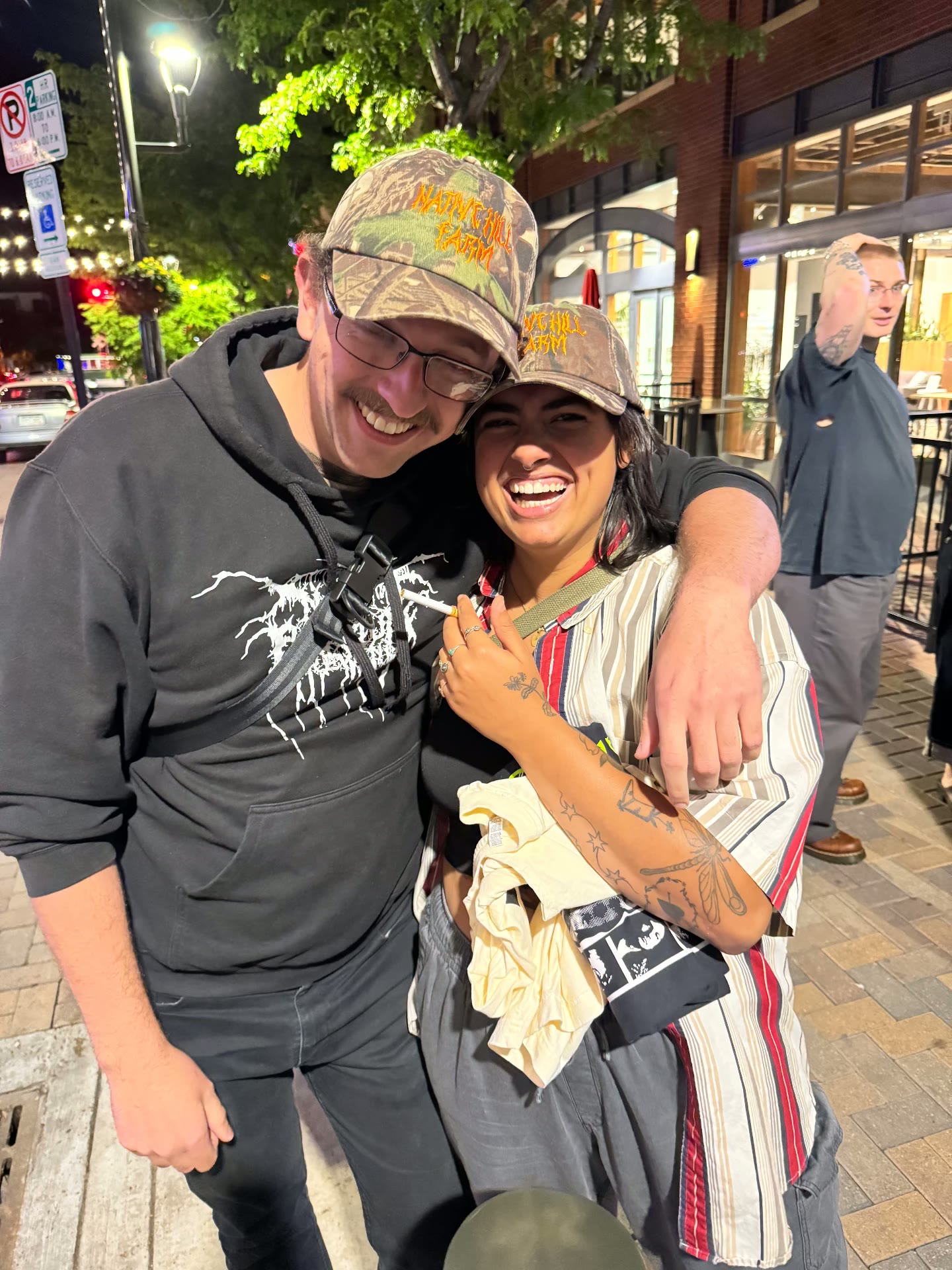 Two people wearing the camo death metal Native Hill Farm hats out on the town